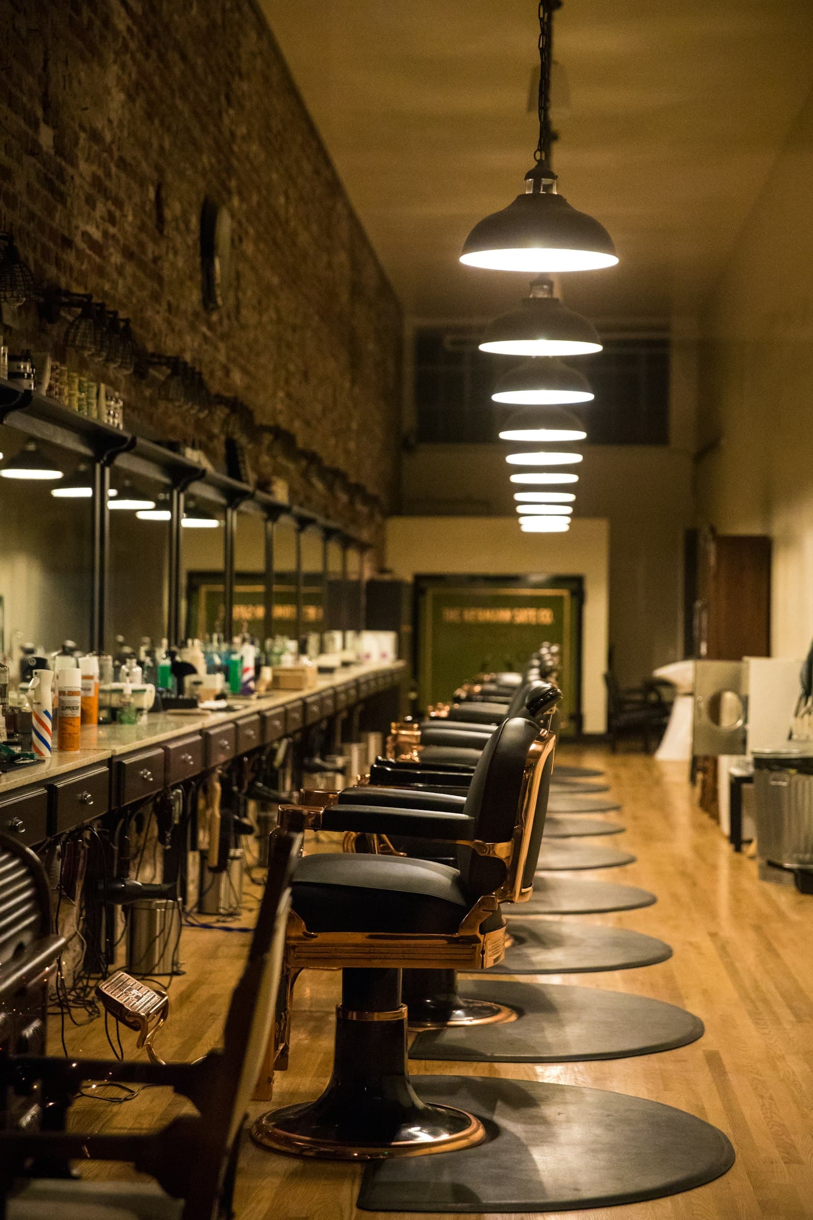 Row of black and copper barber chairs under pendant lamps